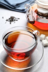Aromatic black tea and sugar cubes on light table, closeup