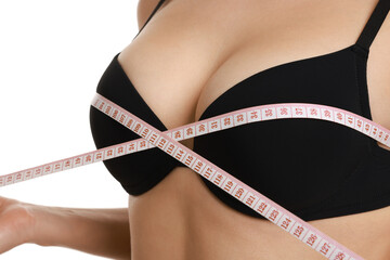 Woman in beautiful bra measuring breast circumference on white background, closeup