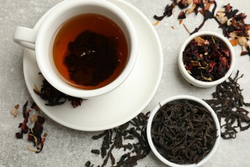 Aromatic tea and dried leaves on grey table, flat lay