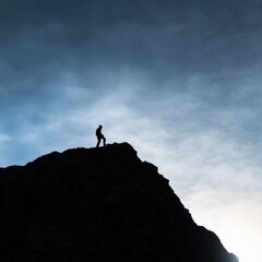 Silhouette of person on top of mountain peak