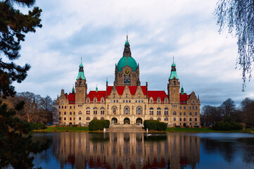 Obraz premium The photo of the old town hall of Hanover with the lake in the foreground and the building, which is illuminated in the afternoon with a glowing facade.