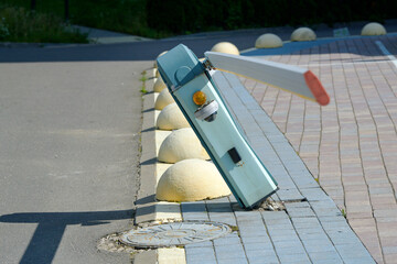 Damaged automatic barrier gates, tilted barrier with torn out fastenings from the sidewalk. Broken automated barrier parking system, boom barrier, parking lot. malfunction in traffic management system