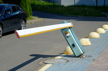 Damaged automatic parking barrier, tilted barrier with torn out fastenings from the sidewalk. Broken parking barrier indicating an accident. Traffic accident. © Tricky Shark