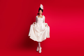 Photo of princess lady in antique dress touch dress jumping isolated red color background