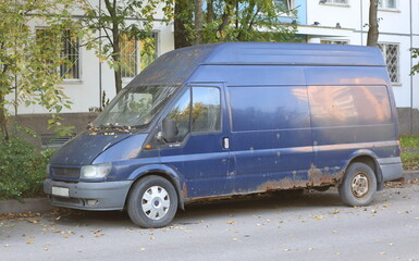 An old rusty blue minibus is parked near a residential building, Bolshevikov Avenue, Saint Petersburg, Russia, October 01, 2024