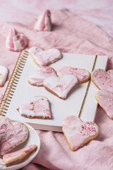 Homemade decorated heart shaped cookies and other sweets on pink background