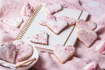 Homemade decorated heart shaped cookies and other sweets on pink background