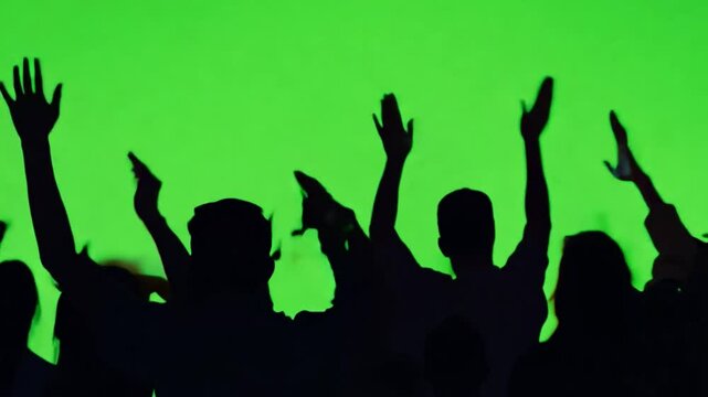 Silhouette of a Cheering Crowd with arms raised on Green Screen:Capturing the energy of a crowd silhouette against the vibrant green screen, hands raised in the air with a sense of freedom and energy.