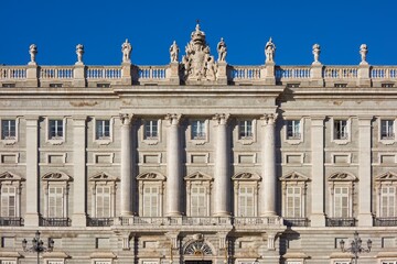 Close-up shot of the Royal Palace of Madrid's facade featuring ornate balconies and four elegant columns. Architectural detail and historical grandeur