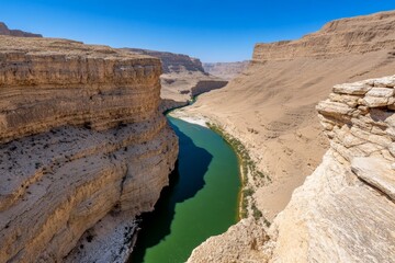 A deep canyon carved between two towering mountains, with a river flowing through it