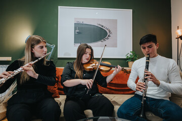 A group of young adults playing flute, violin, and clarinet together in harmony, surrounded by modern decor, showcasing their love for music and passion for collaboration in an intimate setting.