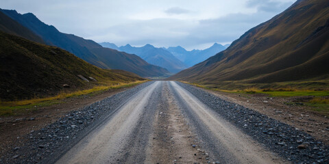 Naklejka premium rugged road stretches through majestic mountains, surrounded by nature beauty. scene evokes sense of adventure and exploration in remote landscape