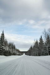 Snow covered road in North Finland on a sunny winter day. Travel Finland landscape background.