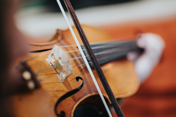 A detailed close-up focusing on a violin being played by a musician in an elegant environment,...