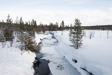 Snow covered river in North Finland on a cloudy day.