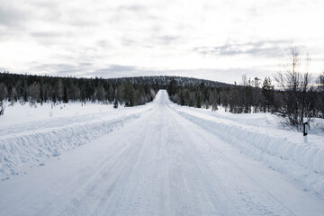 Snow covered road in North Finland on a sunny winter day. Travel Finland landscape background.