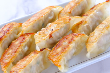 外がパリパリ、中がジューシー、焦げ目がおいしそうな焼きギョウザ
