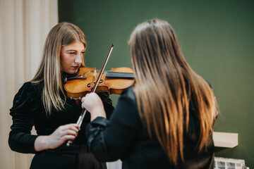 Two young women engaged in violin practice, highlighting dedication and focus in musical training.