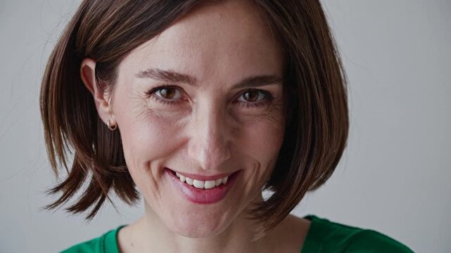 Studio portrait featuring a smiling middle-aged businesswoman radiating confidence and professionalism, set against a neutral background that enhances her approachable demeanor