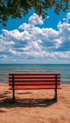 Fototapeta premium Red Bench on Sandy Beach, Inviting Cloudscape, Tranquil Ocean View, Summertime Relaxation