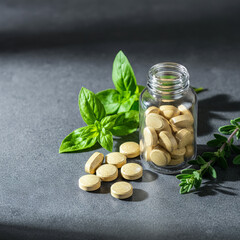 Natural Medicine: Bottle of Pills with Medicinal Herbs and Green Leaves on a soft Background