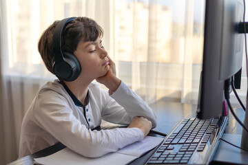 tired little boy 7-9 years old doing homework at home. Topic distance learning, homework, homework, negative impact of distance learning on psychological health. Topic autism, ADHD,. neurodivergence.