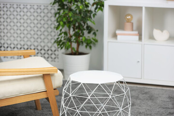 Stylish coffee table near armchair in room