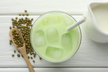 Fresh mung bean juice with ice in glass, milk and seeds on white wooden table, flat lay