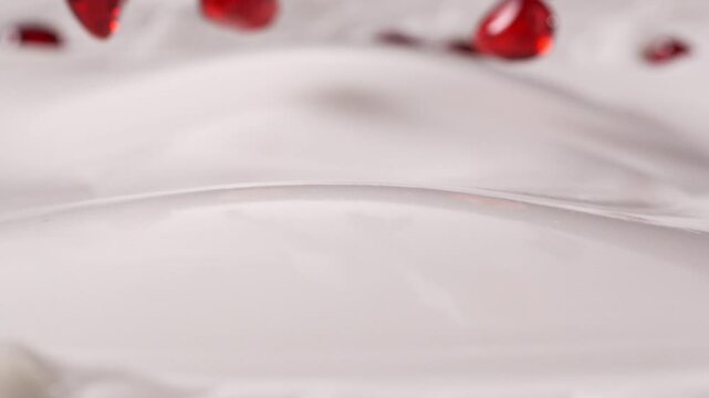 pomegranate arils pouring onto creamy yoghurt mixture