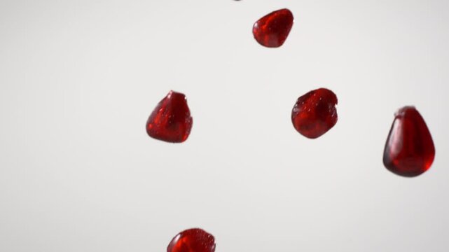 close up shot of pomegranate arils pouring on white background