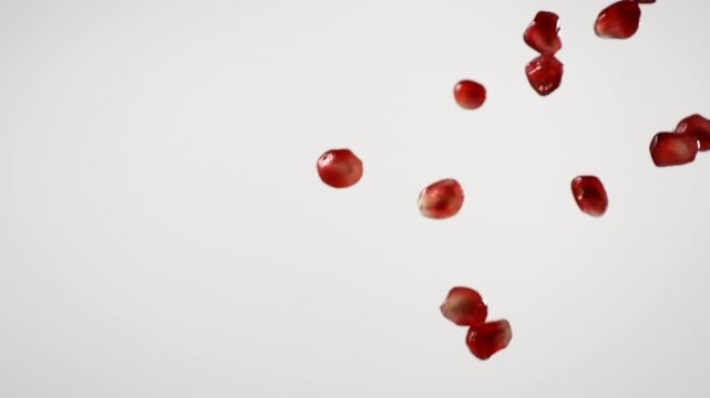 close up shot of pomegranate arils pouring on white background