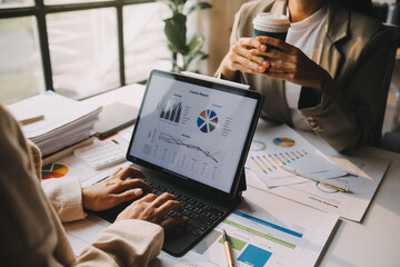 Two young Asian business woman talk, consult, discuss working with new startup project idea presentation analyze plan marketing and investment in the office.