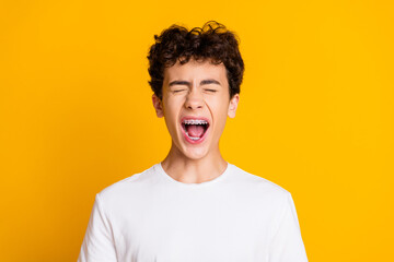 Young male teenager smiling joyfully with braces on yellow background, conveying energy and...