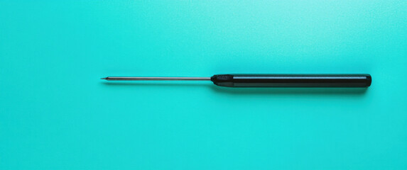 Fototapeta premium A black screwdriver is laid flat against a bright turquoise background, showcasing its sleek design ideal for various tasks and repairs