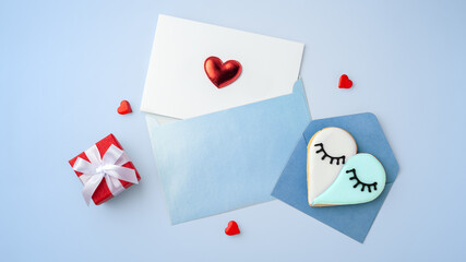 Card with heart in blue envelope and heart shaped cookie, mothers day concept on blue background