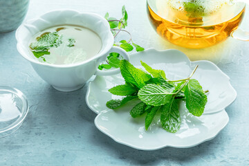 Mint tea. Fresh peppermint leaves with a cup and a tea pot in the background, healthy herbal infusion