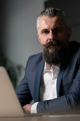 Vertical: Confident businessman, entrepreneur or lawyer sitting at a desk with a laptop, looking...