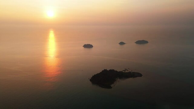 Sunrise reflecting on the calm sea across silhouette of outlying islands and islets in Koh Chang Thailand