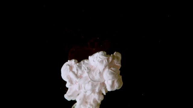 white paint cloud explosion in water on black background