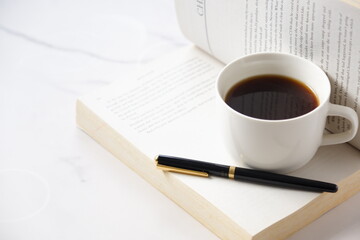 コーヒーを飲みながら、のんびりペーパーバック（洋書）を読んでいるイメージ
