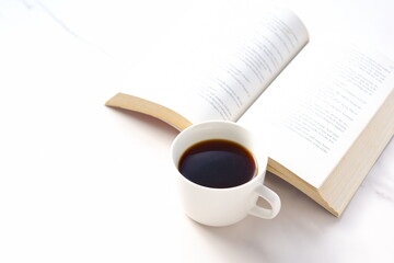 コーヒーを飲みながら、のんびりペーパーバック（洋書）を読んでいるイメージ
