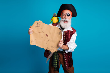 Photo portrait of old funny pirate male hold treasure map dressed carnival party costume party isolated blue color background