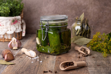 Half-sour dill pickle (quick pickled cucumbers) in a jar with seasonings, spices and herbs. Homemade seasonal preparations. Traditional canning of vegetables. Selective focus, close-up.