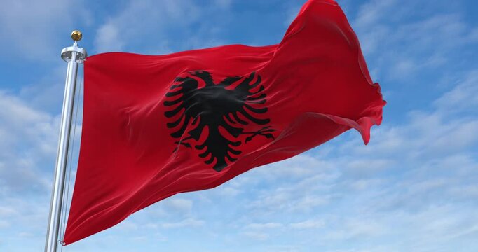 Albania flag with flagpole waving in wind, rolling clouds background looping, 4K video (Perfect Loop)