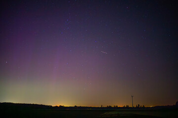 Fototapeta premium beautiful colorful aurora borealis over fields and meadows. amazing phenomenon in the sky at night in Poland. dark sky at night, colors in the night sky. magnetic storm.