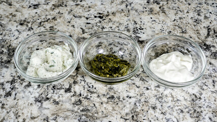 Variety of sauces displayed in small glass bowls on a granite countertop