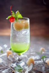 A glass of green cocktail with a red flower on the top