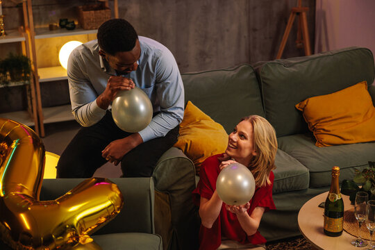 Friends blowing up balloons, preparing for birthday party celebration - Powered by Adobe