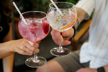 Friends toasting with colorful cocktails in large glasses
