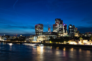 Naklejka premium London City Skyline at Night With Illuminated Skyscrapers and Thames Reflections